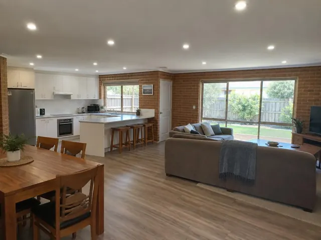 Open-plan kitchen and living room with recessed LED downlights in a brick home in Charmhaven